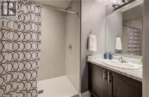 Walk-in shower with tiled walls and a white base, complemented by a vanity featuring a granite-look countertop and an integrated sink - 35 Greyhawk Street, Kitchener, ON 