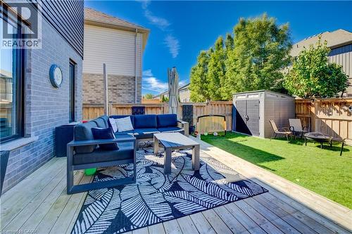 Expansive wood-finish deck with a built-in privacy wall, artificial turf lawn, privacy fencing, and a storage shed - 35 Greyhawk Street, Kitchener, ON 