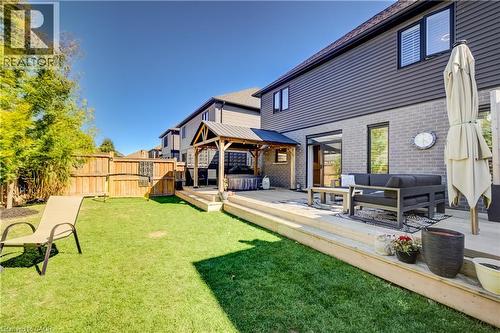 Expansive lawn area with a wooden fence boundary, featuring a multi-level wooden deck - 35 Greyhawk Street, Kitchener, ON 