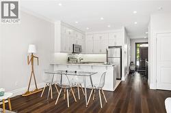 Kitchen featuring white cabinetry, stainless steel appliances, recessed lighting, and a breakfast bar - 