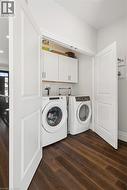 Dedicated laundry area featuring a front-loading washer and dryer, wood-finish flooring, and white cabinetry - 