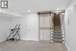 Barn door entry to carpeted stairs, recessed lighting, and a white panel door - 