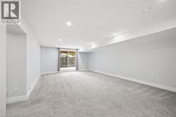 Spacious room featuring light gray carpeting, recessed ceiling lighting, and a sliding glass door - 