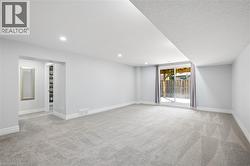 Spacious room featuring light-toned carpeting, recessed ceiling lighting, and a sliding glass door - 