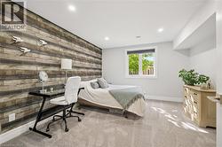 Recessed lighting, wood-finish accent wall, light-colored carpeting, white trim, and a window with a roller blind - 