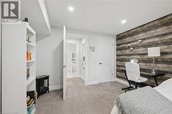 Recessed lighting, wood-finish accent wall, light gray carpeting, and white interior doors - 