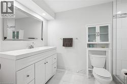 White vanity with integrated sink, rectangular framed mirror, recessed lighting, and over-toilet storage cabinet - 