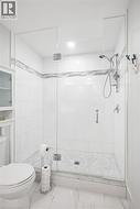 Glass-enclosed shower with a tiled surround, integrated grab bar, and a handheld shower fixture - 