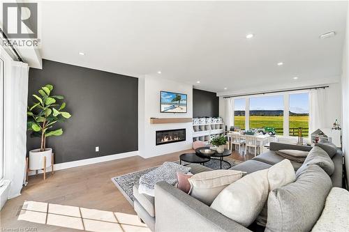 Recessed ceiling lighting, light wood-finish flooring, linear fireplace with wood mantel, built-in shelving, and expansive windows - 5367 2 Side Road, Milton, ON 