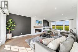 Recessed ceiling lighting, light wood-finish flooring, linear fireplace with wood mantel, built-in shelving, and expansive windows - 
