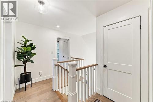 Hardwood flooring, white painted walls, white railing, natural wood-finish handrail, and a contemporary flush mount light fixture - 5367 2 Side Road, Milton, ON 