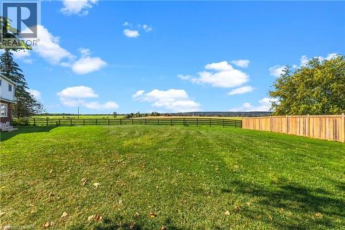 Expansive green space featuring a wood fence, a black wire fence, and mature trees - 5367 2 Side Road, Milton, ON 