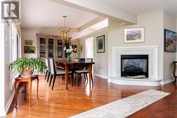 Hardwood flooring, fireplace with a marble-look surround, tray ceiling, recessed lighting, and a gold-finish chandelier - 