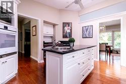 Kitchen featuring a center island with sink, dark countertop, and white cabinetry - 
