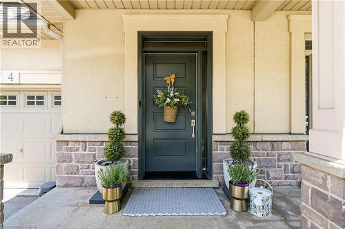 Entry featuring a dark-toned door with a transom, stucco siding, and a stone facade - 5056 New Street Unit# 4, Burlington, ON 