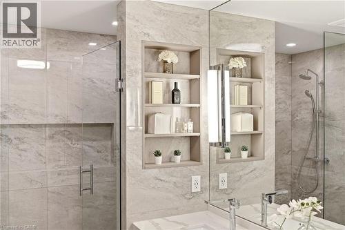 Shower featuring a frameless glass enclosure, recessed storage niche, and a rain showerhead with an additional handheld sprayer - 5056 New Street Unit# 4, Burlington, ON 