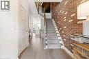 Hardwood-finish flooring, exposed brick wall, carpeted staircase, white-painted trim, and built-in recessed lighting - 5056 New Street Unit# 4, Burlington, ON 