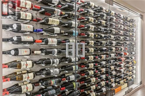 Dedicated wine storage room featuring glass entry doors, custom wall-mounted wine racks, and integrated perimeter lighting - 5056 New Street Unit# 4, Burlington, ON 