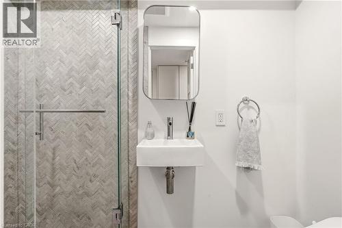 Glass-enclosed shower with herringbone tile, wall-mounted sink, and modern mirror - 5056 New Street Unit# 4, Burlington, ON 