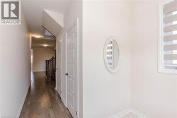 Hallway featuring wood-finish flooring, recessed lighting, and white paneled doors - 