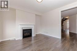Wall-mounted fireplace with mantel, hardwood-style flooring, and recessed ceiling lighting - 