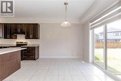 Dark wood-finish cabinetry, light-toned countertops, tile flooring, and a sliding glass door with a built-in shade - 