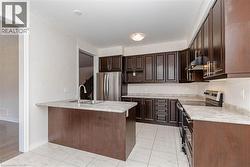 Kitchen featuring rich wood-finish cabinetry, light-toned countertops, stainless steel appliances, and tiled flooring - 