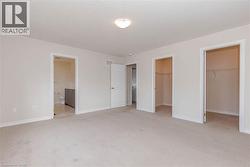 Plush carpet flooring, neutral wall tones, two integrated closet spaces, and an attached full bathroom featuring tiled flooring and a vanity with an integrated sink - 