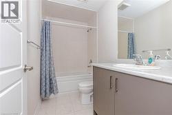 Modern bathroom featuring a single vanity with a solid surface countertop, an integrated sink, a rectangular mirror, and a shower/tub combination with tiled surround - 
