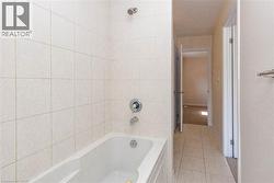 Bathtub with integrated shower, chrome fixtures, and tiled surround - 