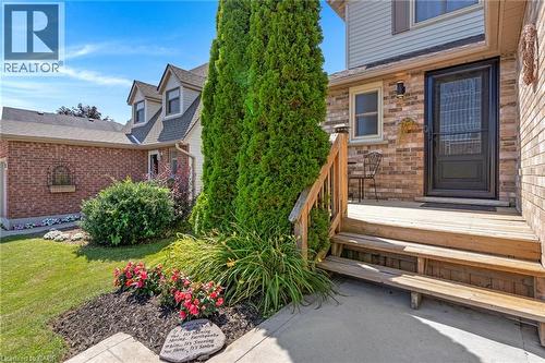 Brick and siding exterior with a wood-finish porch, mature landscaping, and dormer windows - 311 Misty Crescent, Kitchener, ON - Outdoor
