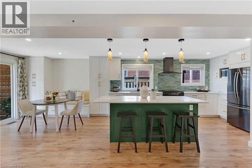 Kitchen featuring a green island, white countertops, stainless steel appliances, wood-finish flooring, and a tiled backsplash - 311 Misty Crescent, Kitchener, ON - Indoor
