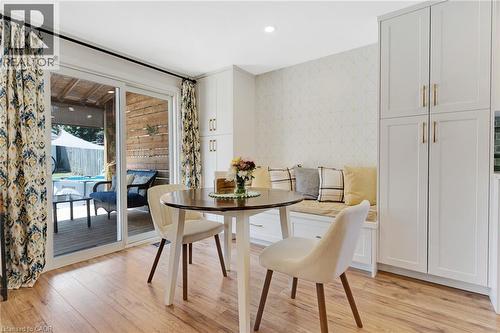 Wood-finish flooring, built-in storage bench, recessed lighting, white built-in cabinetry with gold-tone hardware, and sliding glass door leading to an outdoor deck - 311 Misty Crescent, Kitchener, ON - Indoor Photo Showing Dining Room