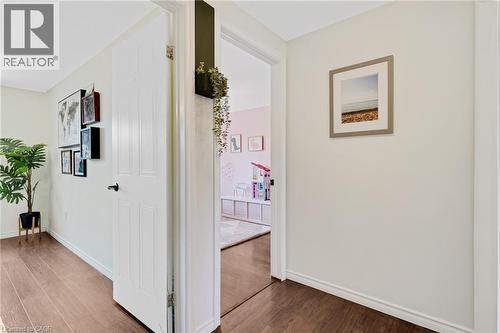 Wood-finish flooring throughout, bright white walls, and a white paneled door with a matte black handle - 311 Misty Crescent, Kitchener, ON - Indoor Photo Showing Other Room