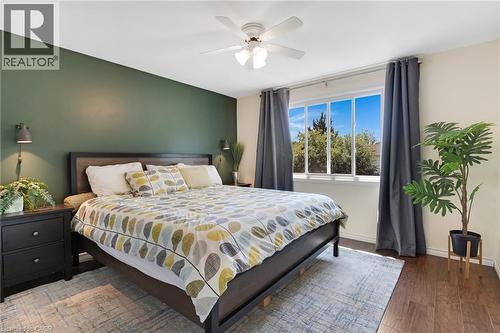 Hardwood-style flooring, a large window, a ceiling fan with integrated lighting, and a feature wall - 311 Misty Crescent, Kitchener, ON - Indoor Photo Showing Bedroom