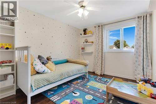 Dark wood-finish flooring, built-in shelving, white ceiling fan, and a single window with white trim - 311 Misty Crescent, Kitchener, ON - Indoor Photo Showing Bedroom