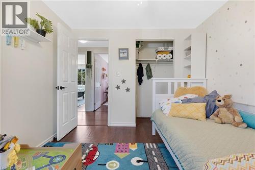 Wood-finish flooring, white paneled doors with black hardware, built-in shelving, and a closet with shelving - 311 Misty Crescent, Kitchener, ON - Indoor Photo Showing Bedroom