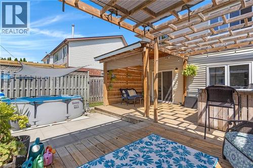 Expansive multi-level wood decking with a wood pergola, featuring a built-in outdoor bar - 311 Misty Crescent, Kitchener, ON - Outdoor With Above Ground Pool With Deck Patio Veranda With Exterior