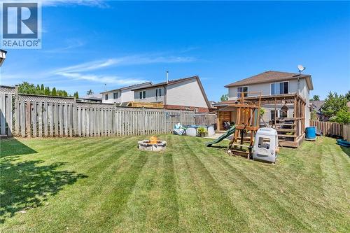 Expansive backyard featuring a manicured lawn, full privacy fencing, a stone-lined fire pit, and a multi-level wood deck - 311 Misty Crescent, Kitchener, ON - Outdoor