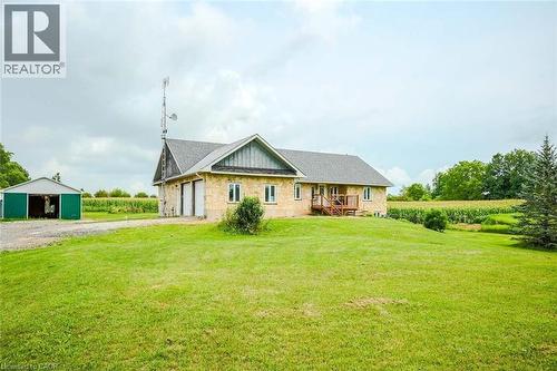 Stone-clad exterior with a gray shingle roof, featuring an attached garage with two white doors - 107 6Th Line Line, Haldimand, ON - Outdoor
