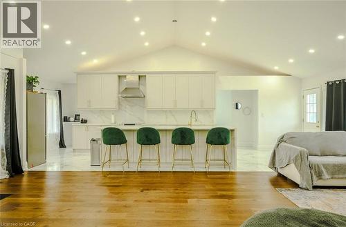 Vaulted ceiling with recessed lighting, wood-finish flooring, kitchen island with built-in cabinetry, stainless steel range hood, and marble-finish backsplash - 107 6Th Line Line, Haldimand, ON - Indoor Photo Showing Living Room