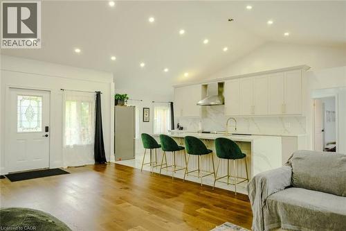 Spacious interior with wood-finish flooring, vaulted ceilings, recessed lighting, and a kitchen featuring a large island with white cabinetry and a stainless steel range hood - 107 6Th Line Line, Haldimand, ON - Indoor