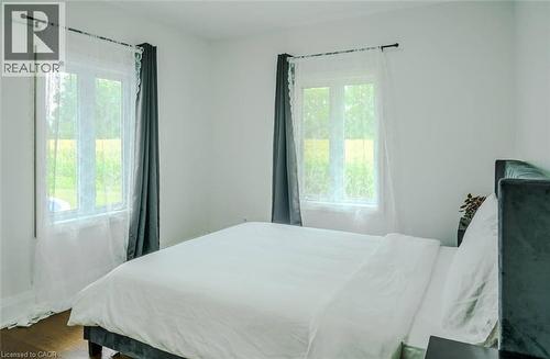 White walls, wood-finish flooring, and multiple windows with trim - 107 6Th Line Line, Haldimand, ON - Indoor Photo Showing Bedroom