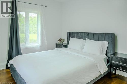 Hardwood flooring, white painted walls, and a window with sheer and solid drapes - 107 6Th Line Line, Haldimand, ON - Indoor Photo Showing Bedroom