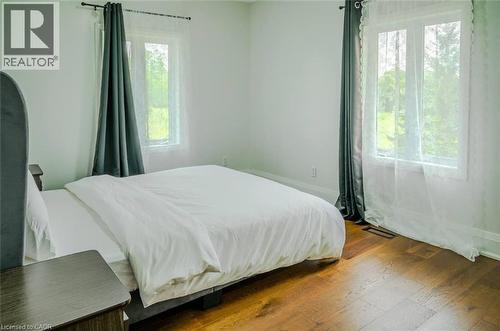Hardwood flooring throughout, featuring two large windows with white trim, and white wall finishes - 107 6Th Line Line, Haldimand, ON - Indoor Photo Showing Bedroom