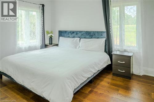 Hardwood flooring throughout, bright white walls, and a tufted fabric headboard - 107 6Th Line Line, Haldimand, ON - Indoor Photo Showing Bedroom