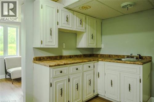 White cabinetry with dark hardware, L-shaped countertop, stainless steel sink, and wood-finish flooring - 107 6Th Line Line, Haldimand, ON - Indoor