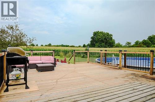 Expansive wood-finish deck with a black metal and wood railing system, featuring an above-ground pool with a blue liner - 107 6Th Line Line, Haldimand, ON - Outdoor With Above Ground Pool