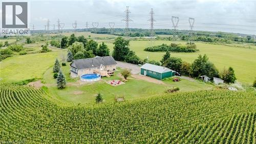 Expansive rural property featuring a primary residence with a deck, a circular above-ground pool, a detached green outbuilding, and surrounding cultivated fields - 107 6Th Line Line, Haldimand, ON - Outdoor With View