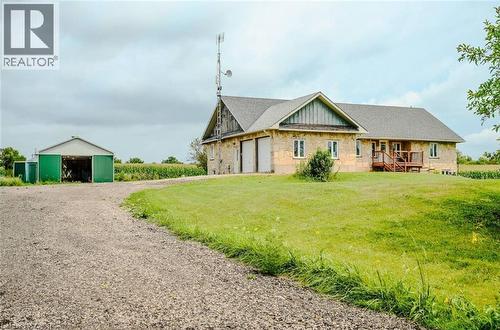 Stone-clad residence featuring an attached garage, a wooden deck, and a detached green outbuilding - 107 6Th Line Line, Haldimand, ON - Outdoor